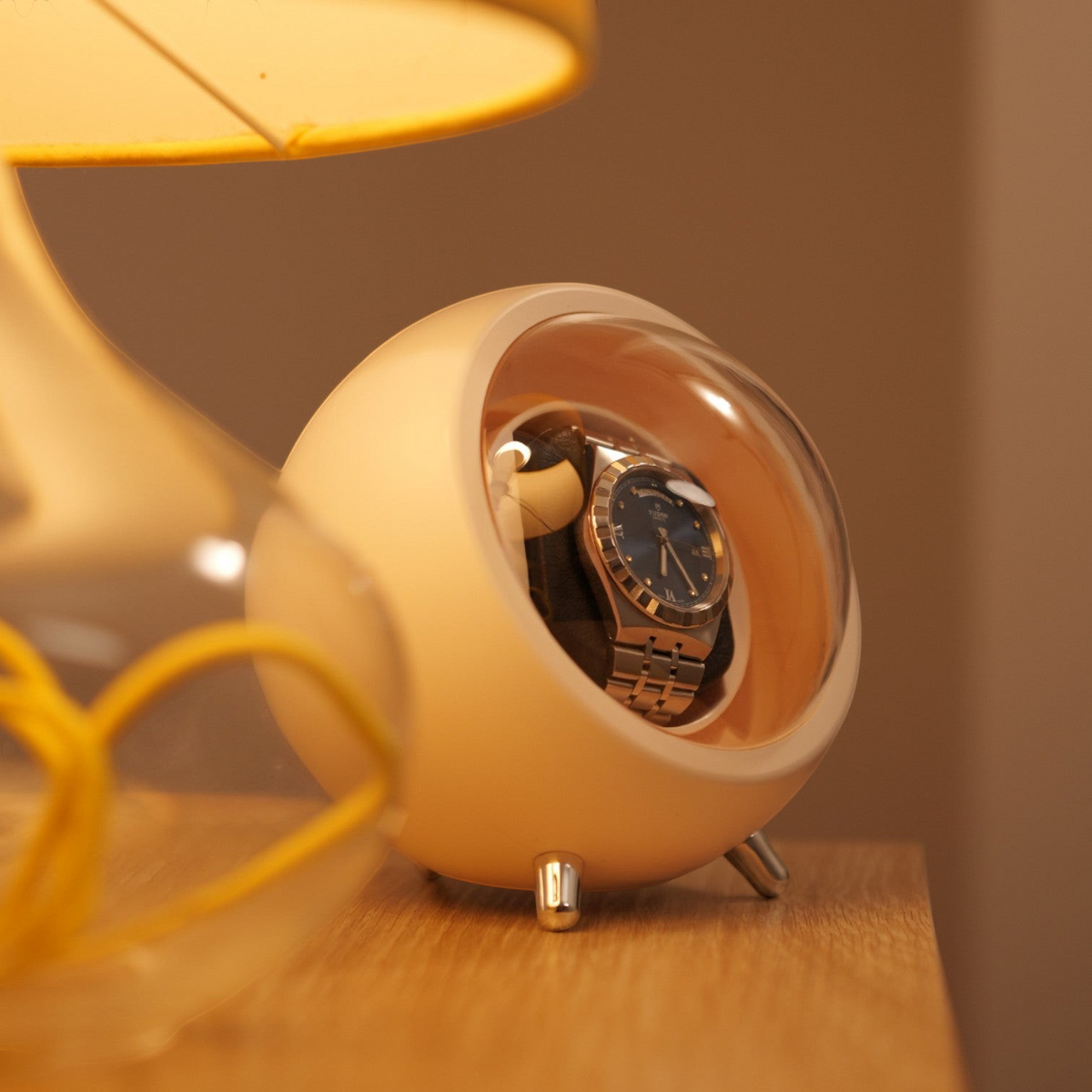 Remontoir de montre Winderly Cyclops blanc avec couvercle signature, contenant une montre automatique sur socle