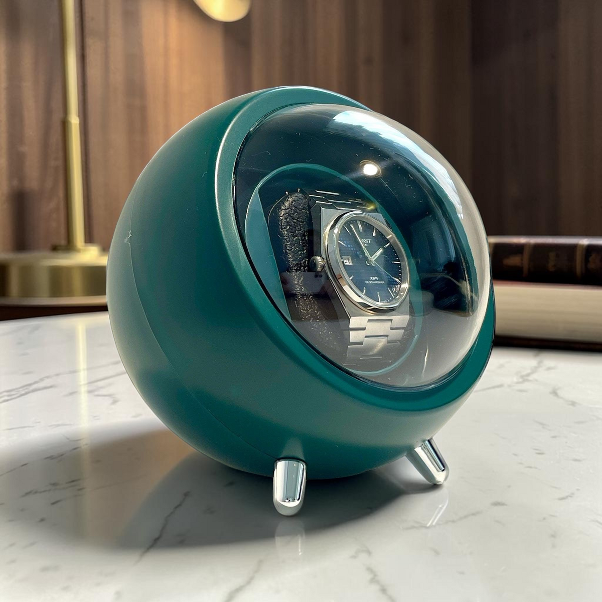 Winderly Cyclops montre automatique verte avec couvercle sphérique transparent et pieds argentés sur table