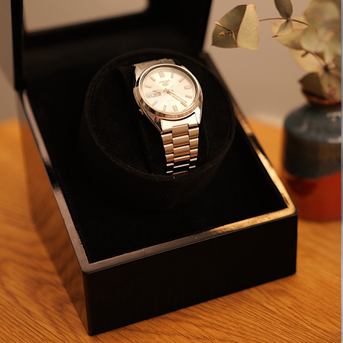 Remontoir de montre automatique Winderly Carina noir brillant avec une montre à cadran argenté sur un support en velours